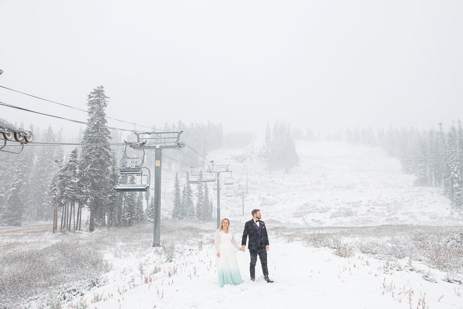 Skiers ride a chairlift through snowy conditions at a mountain resort during winter weather.