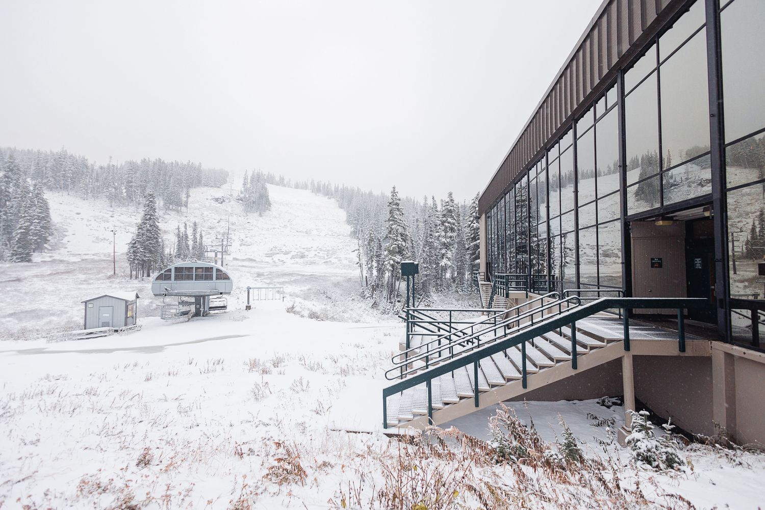 A snowy winter landscape with ski slopes and resort buildings visible through a panoramic window view.