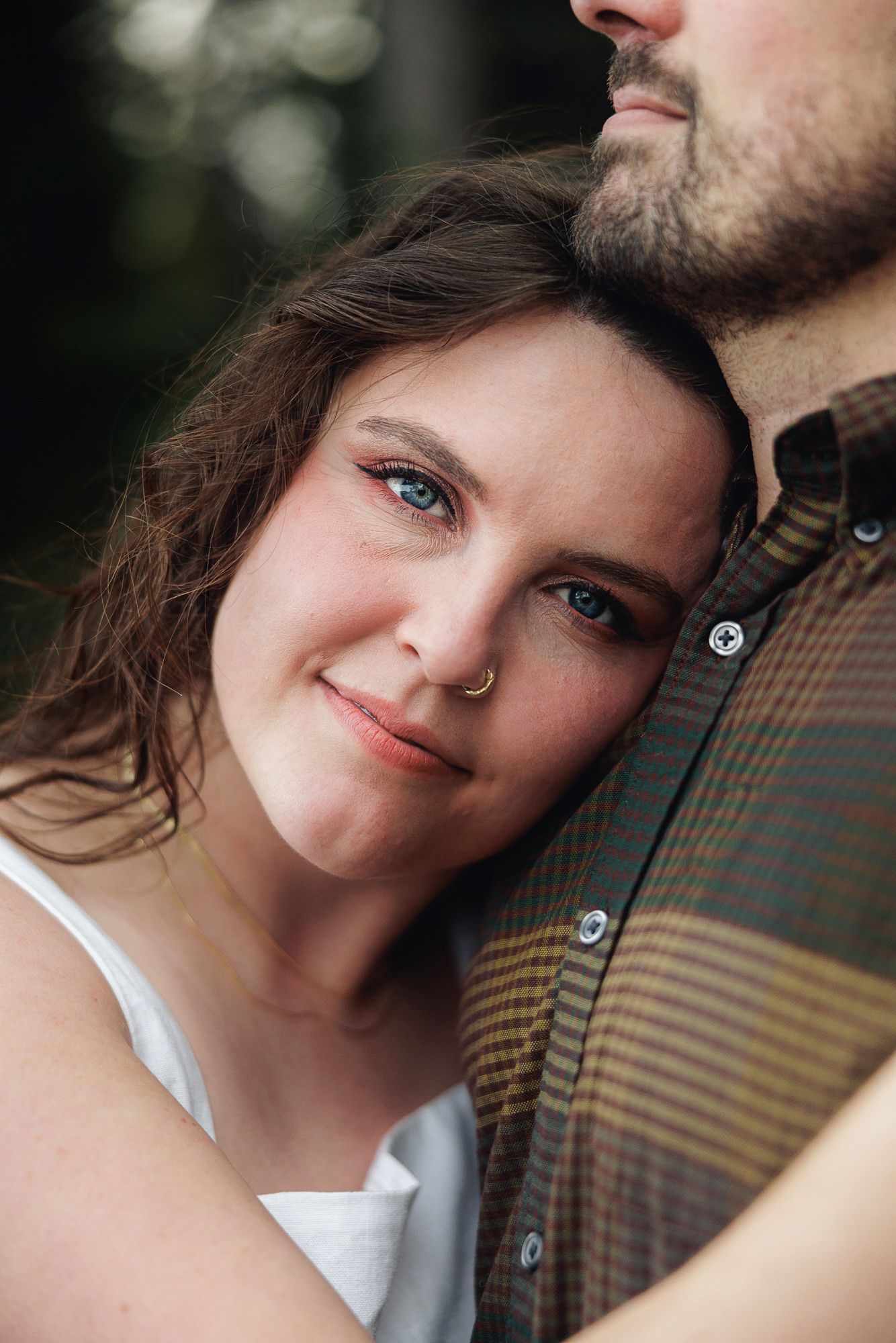 Close up portrait of a couple embracing outdoors with soft bokeh background.