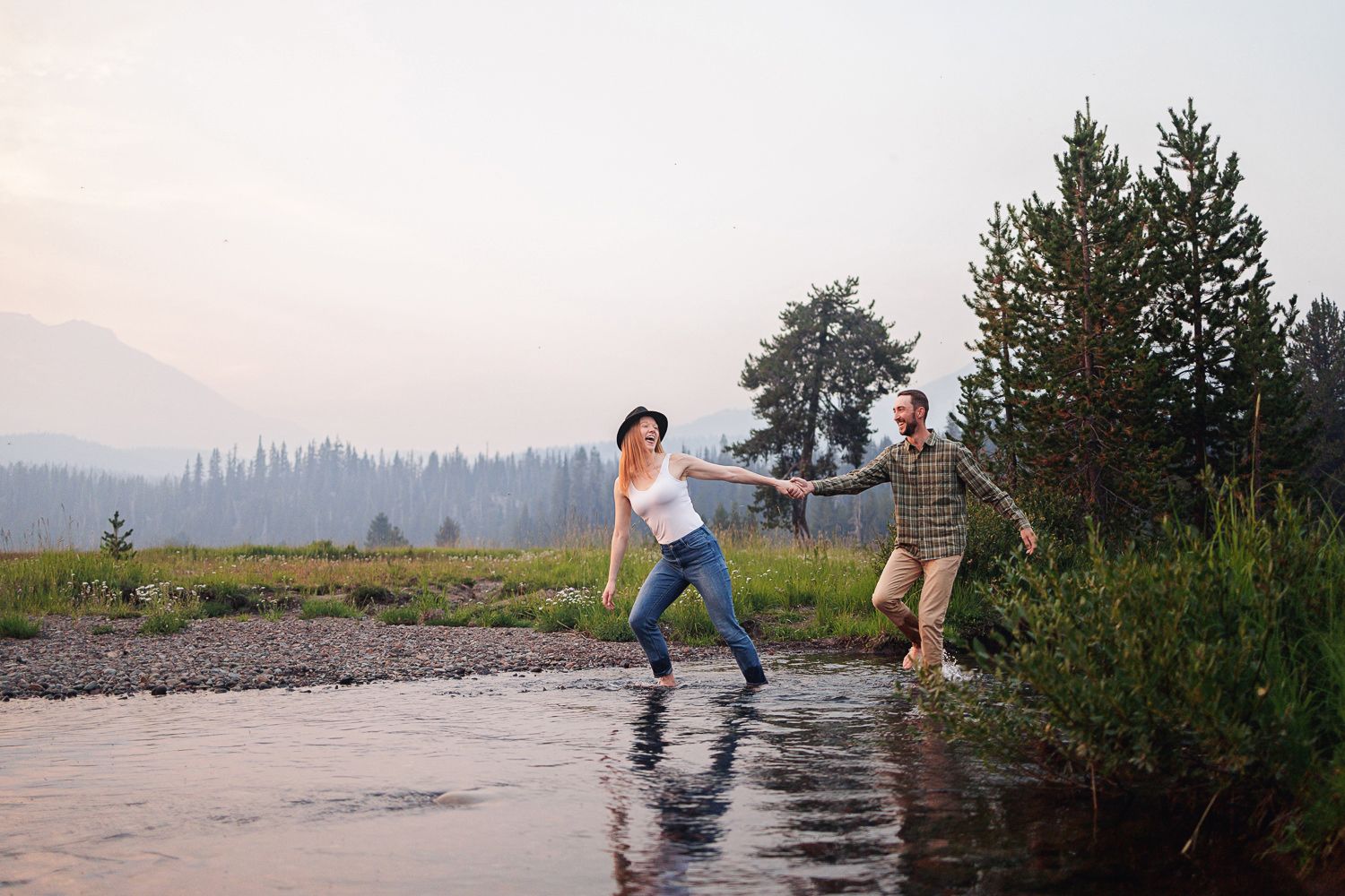 On a misty river shoreline at sunset, a group skips stones across the tranquil water surface.