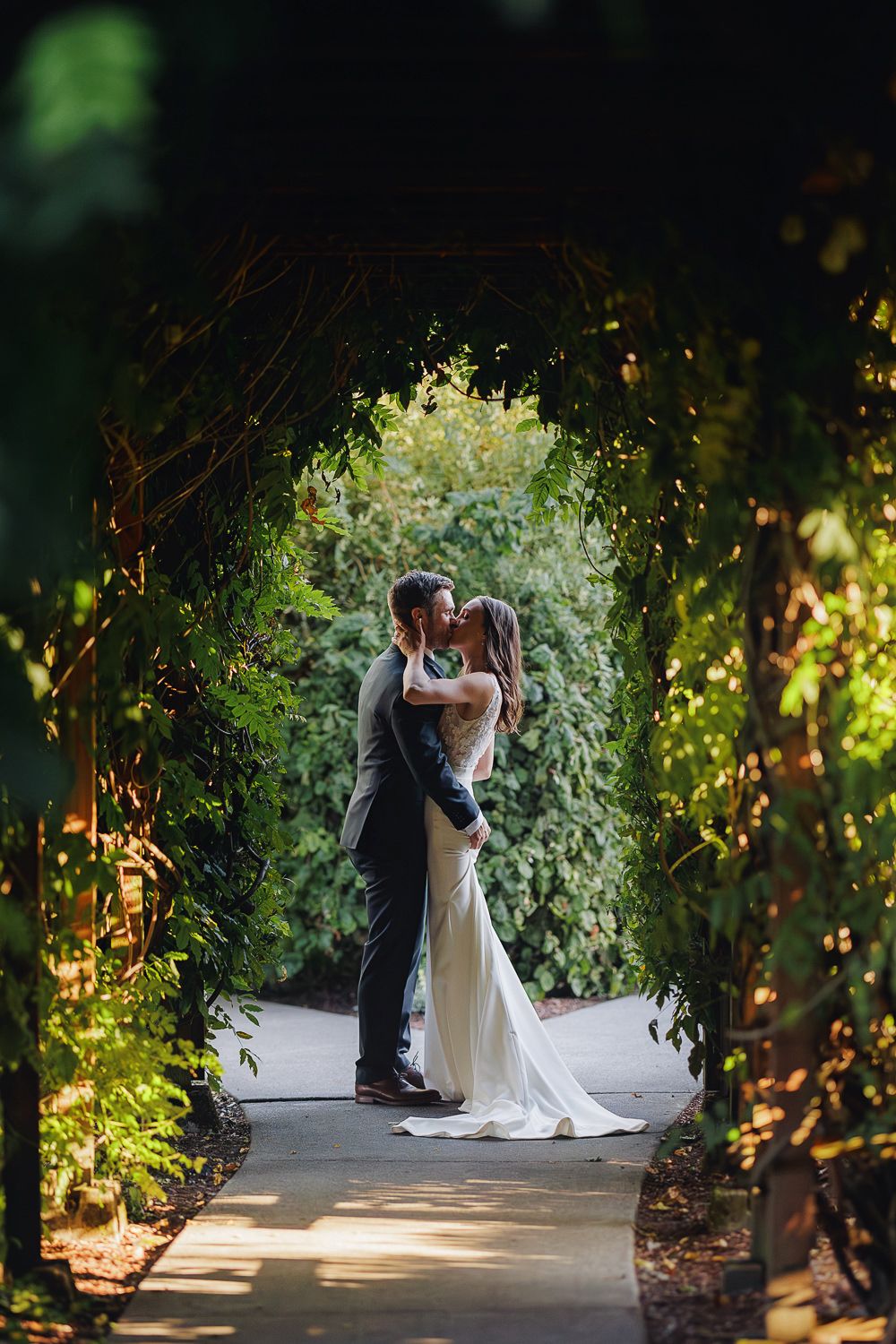 A romantic garden wedding scene with couple embracing under lush greenery and natural lighting.