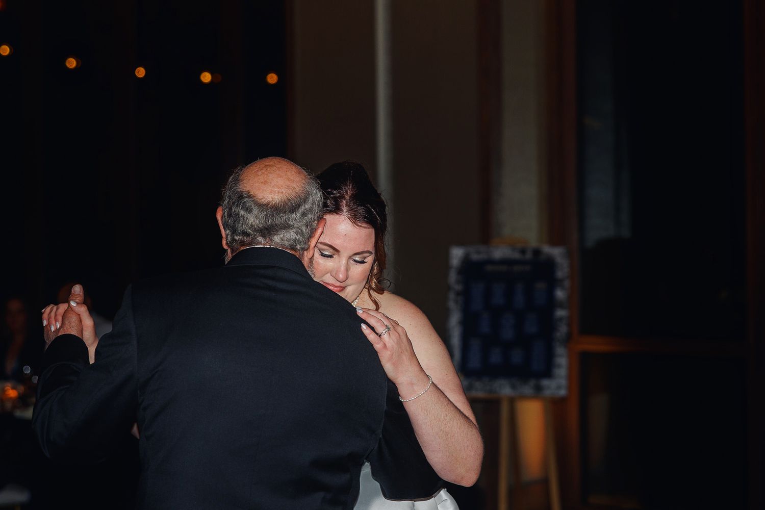 Couple enjoys an intimate moment at their wedding reception in a dimly lit venue with string lights.