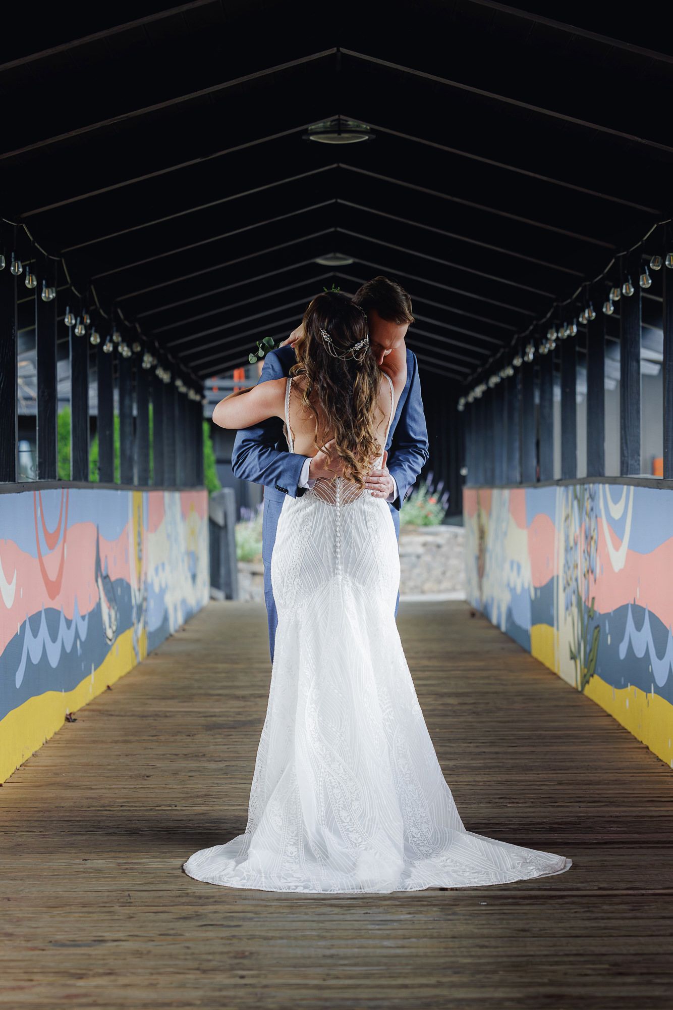 White wedding dress photographed in covered walkway with colorful graffiti walls and wooden flooring.