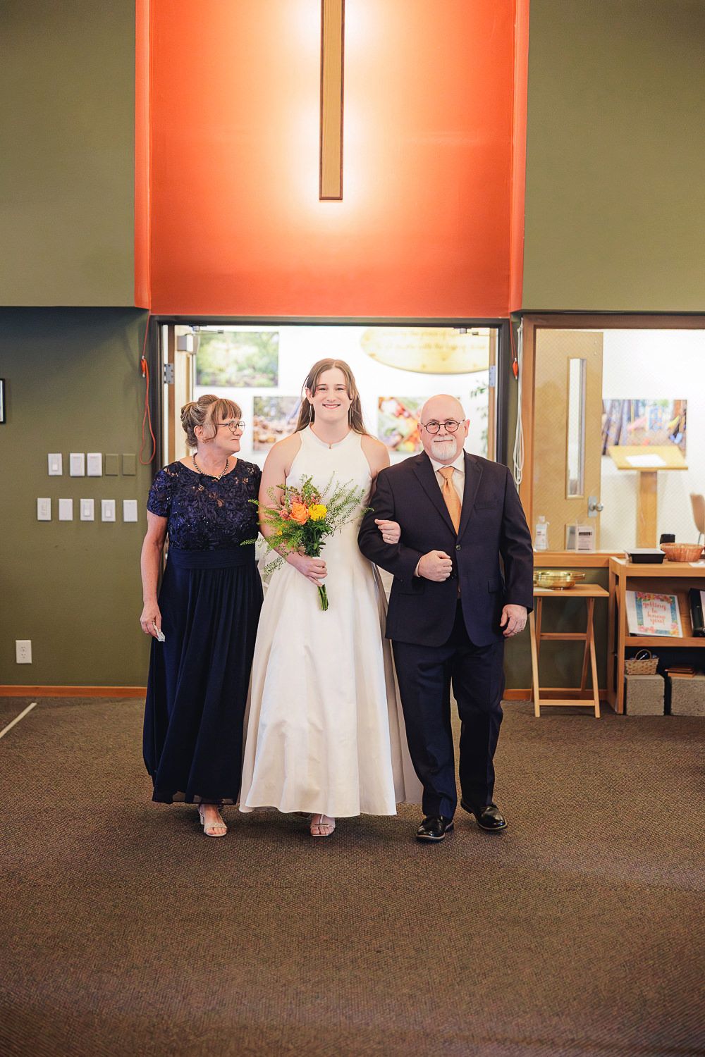 A wedding party poses together in a carpeted room with orange lighting and modern decor.