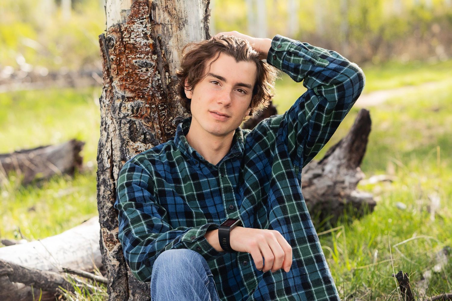 A casual outdoor portrait leaning against a birch tree in a natural setting.