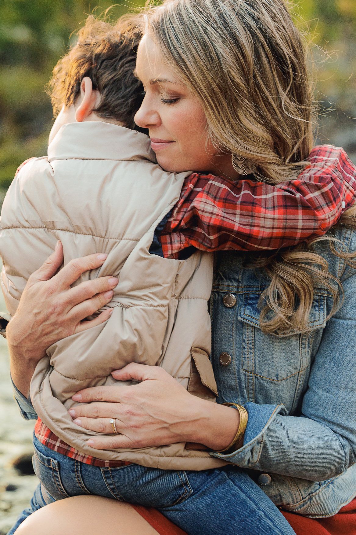 A tender embrace between parent and child wearing winter clothing outdoors.