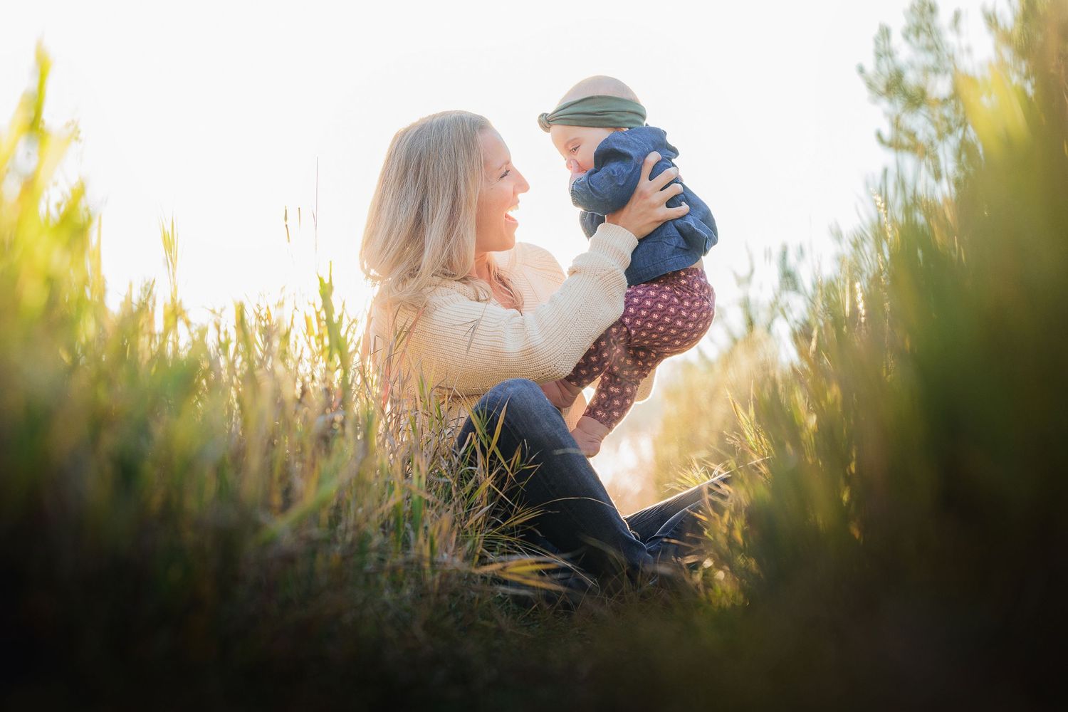 A tender moment between parent and child in golden sunlit tall grass during sunset.