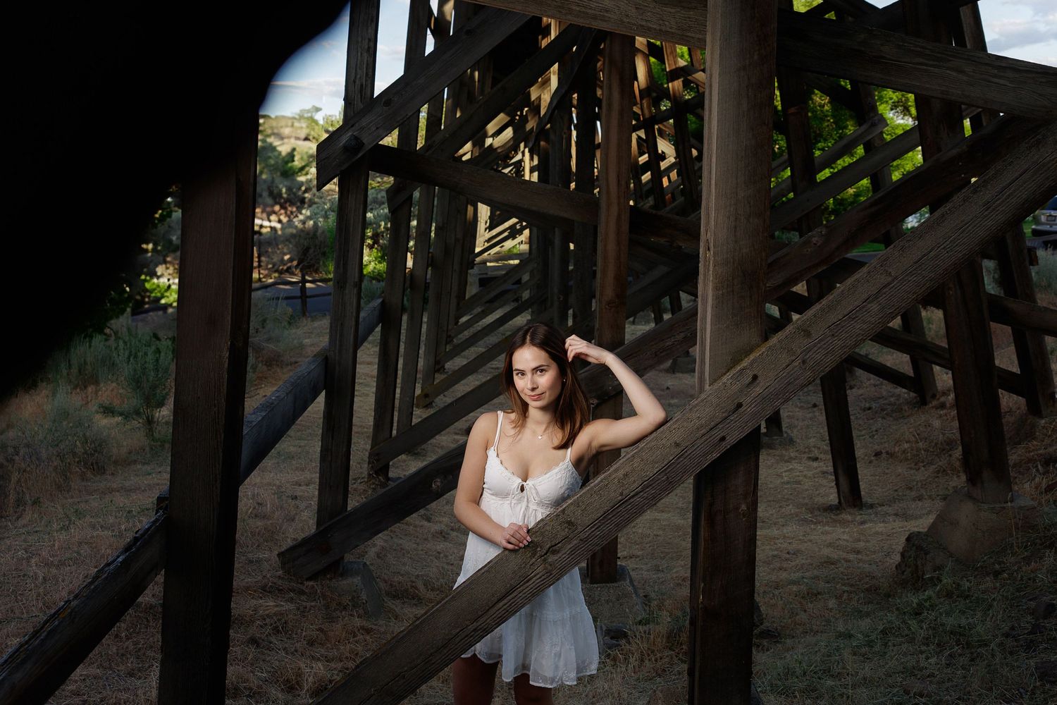 Seven sequential photos show a person in a white dress walking beneath a rustic wooden pier or boardwalk structure.