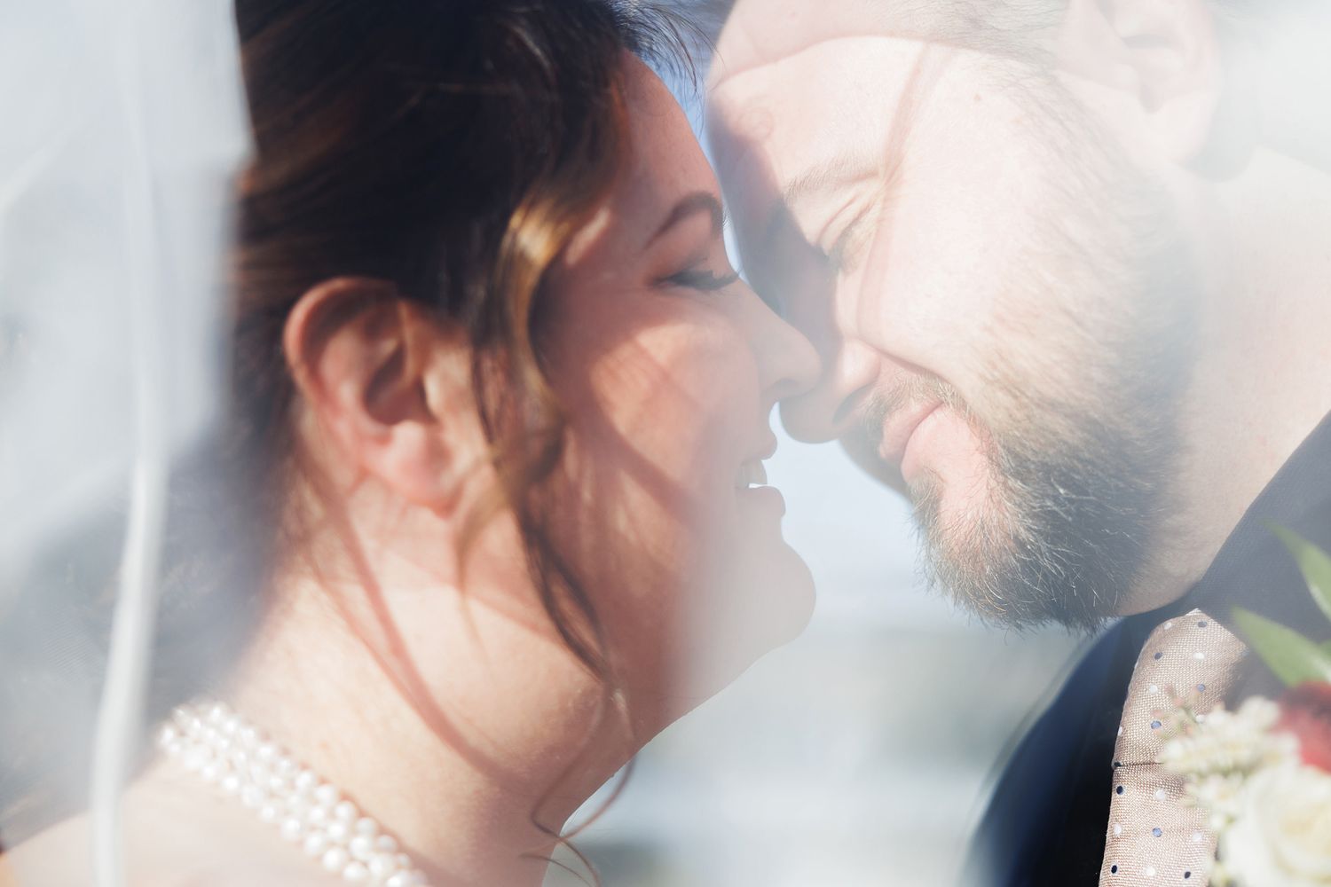 A romantic couple shares a tender kiss while standing close together in soft, dreamy lighting.