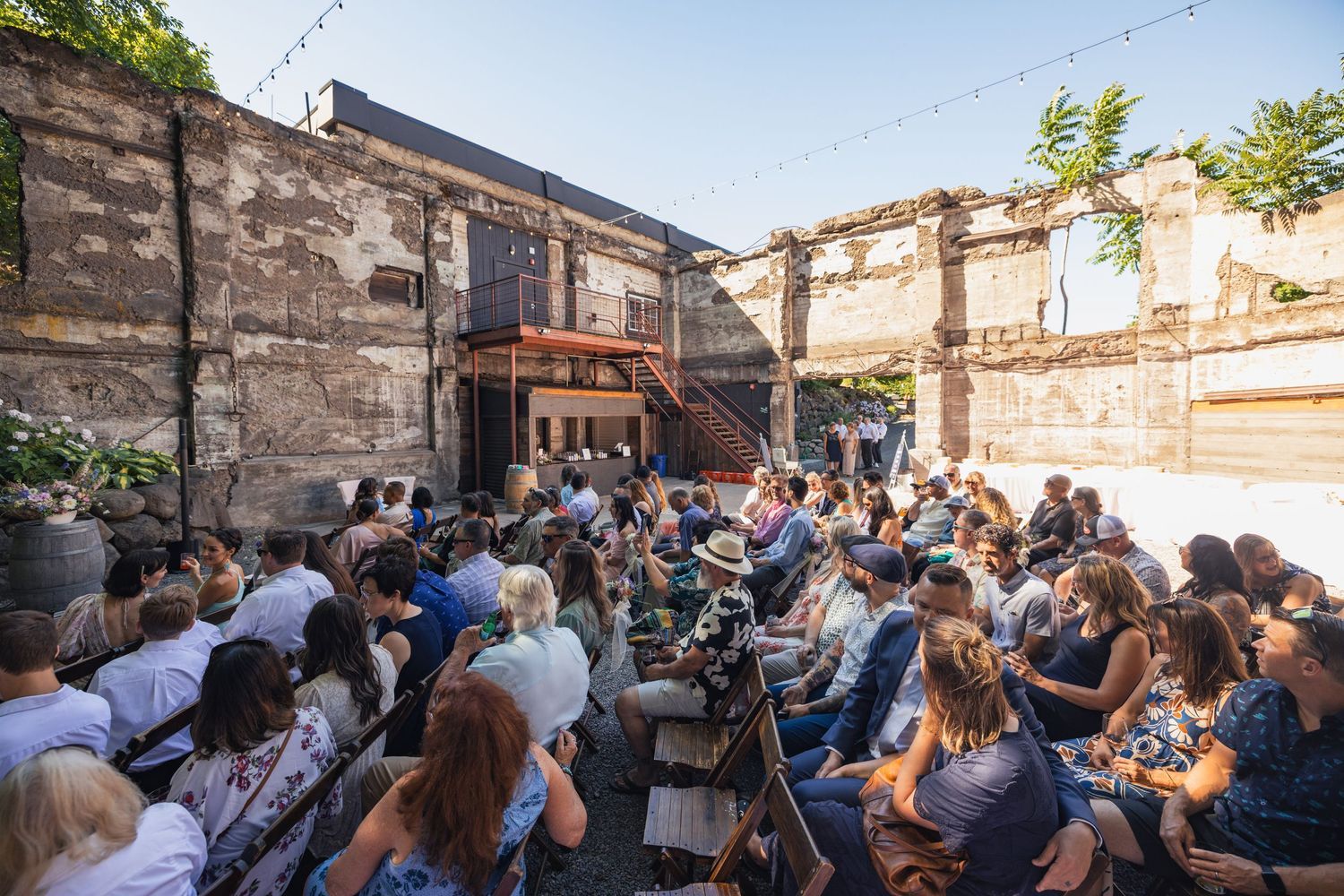 Outdoor amphitheater-style venue filled with audience members seated on rows of chairs for a performance.