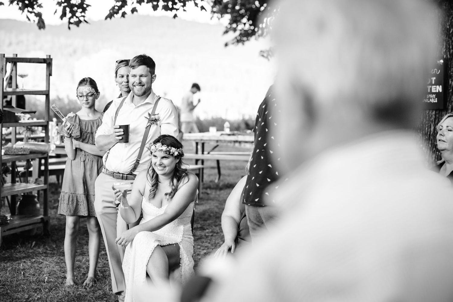 Black and white photo of guests enjoying an outdoor garden party with drinks and casual conversation.