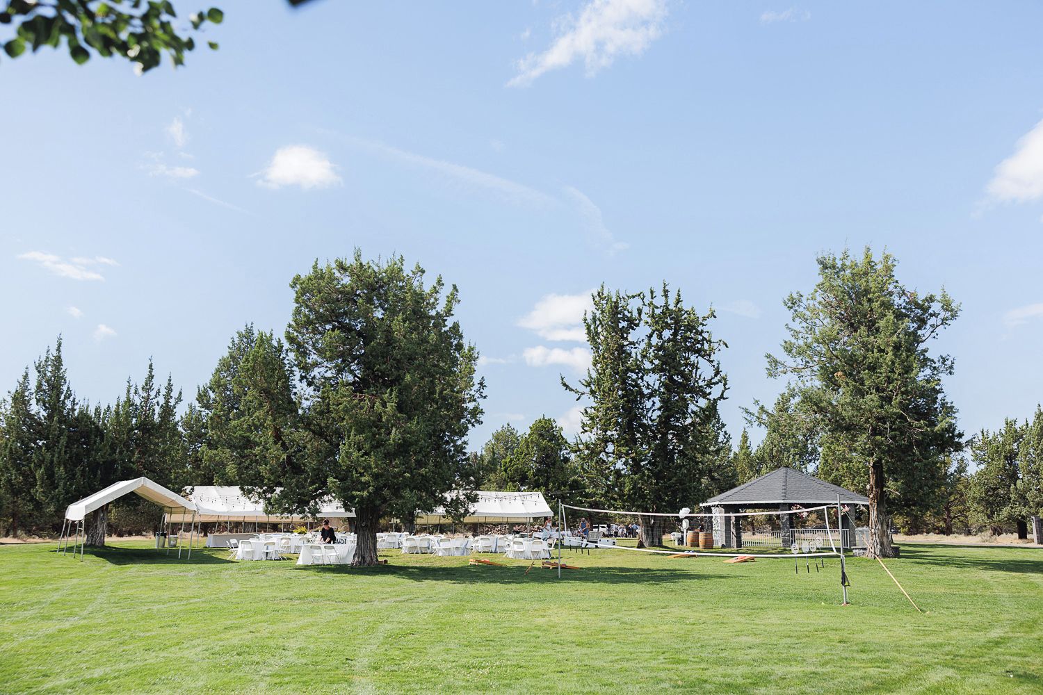 Panoramic view of a rural property with lush greenery, trees, and multiple buildings scattered across the landscape.