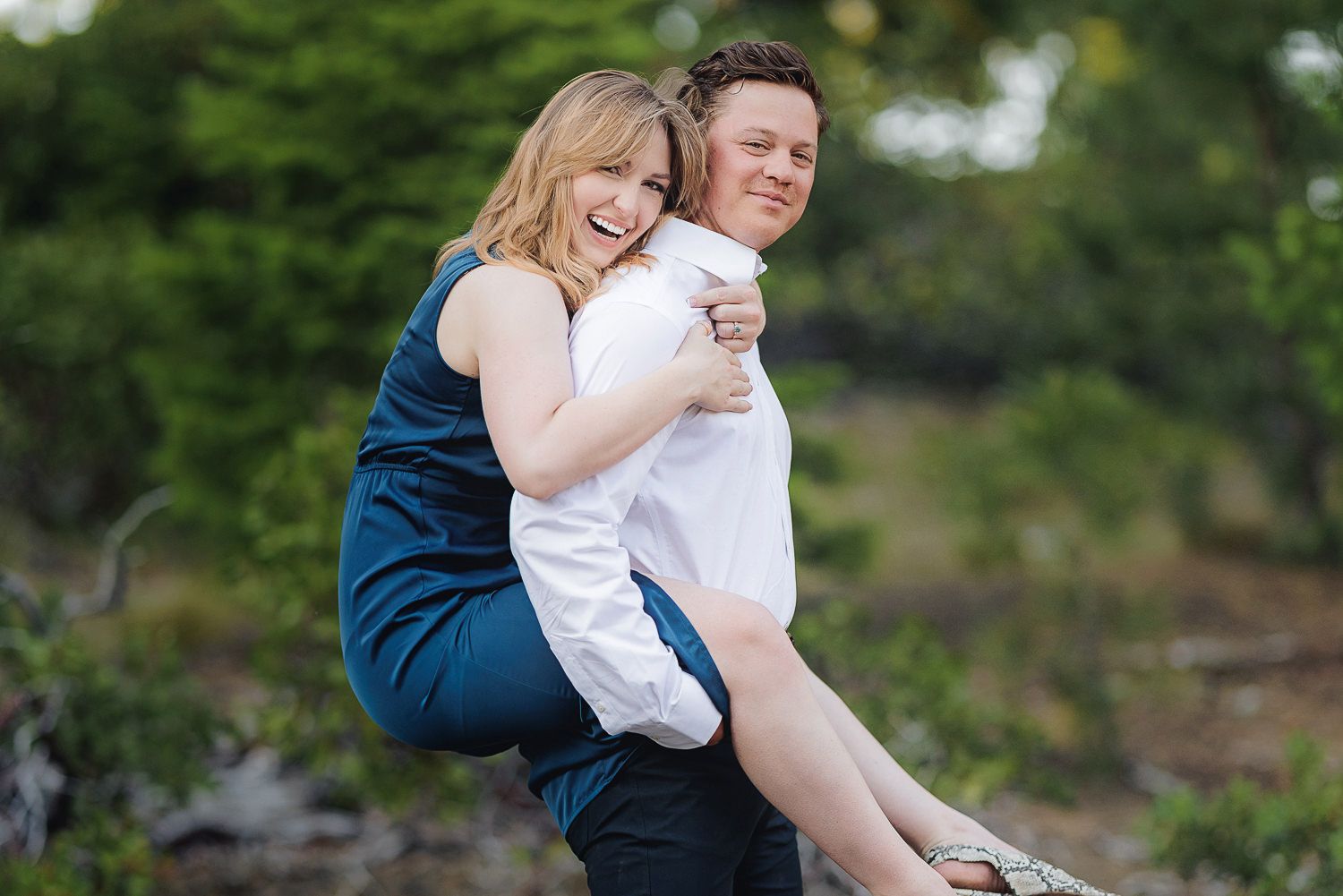 A couple shares a tender moment together on a rocky outdoor setting in casual attire.