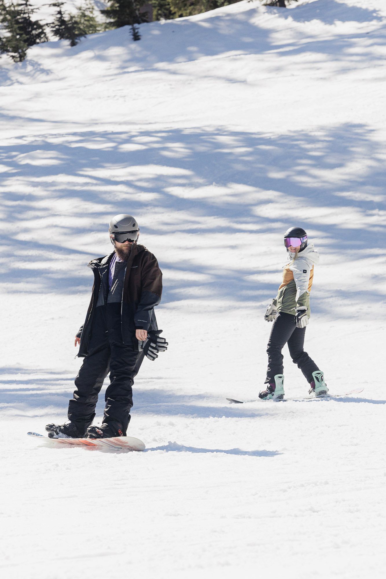 Two people are snowboarding on a snowy slope in a winter landscape.