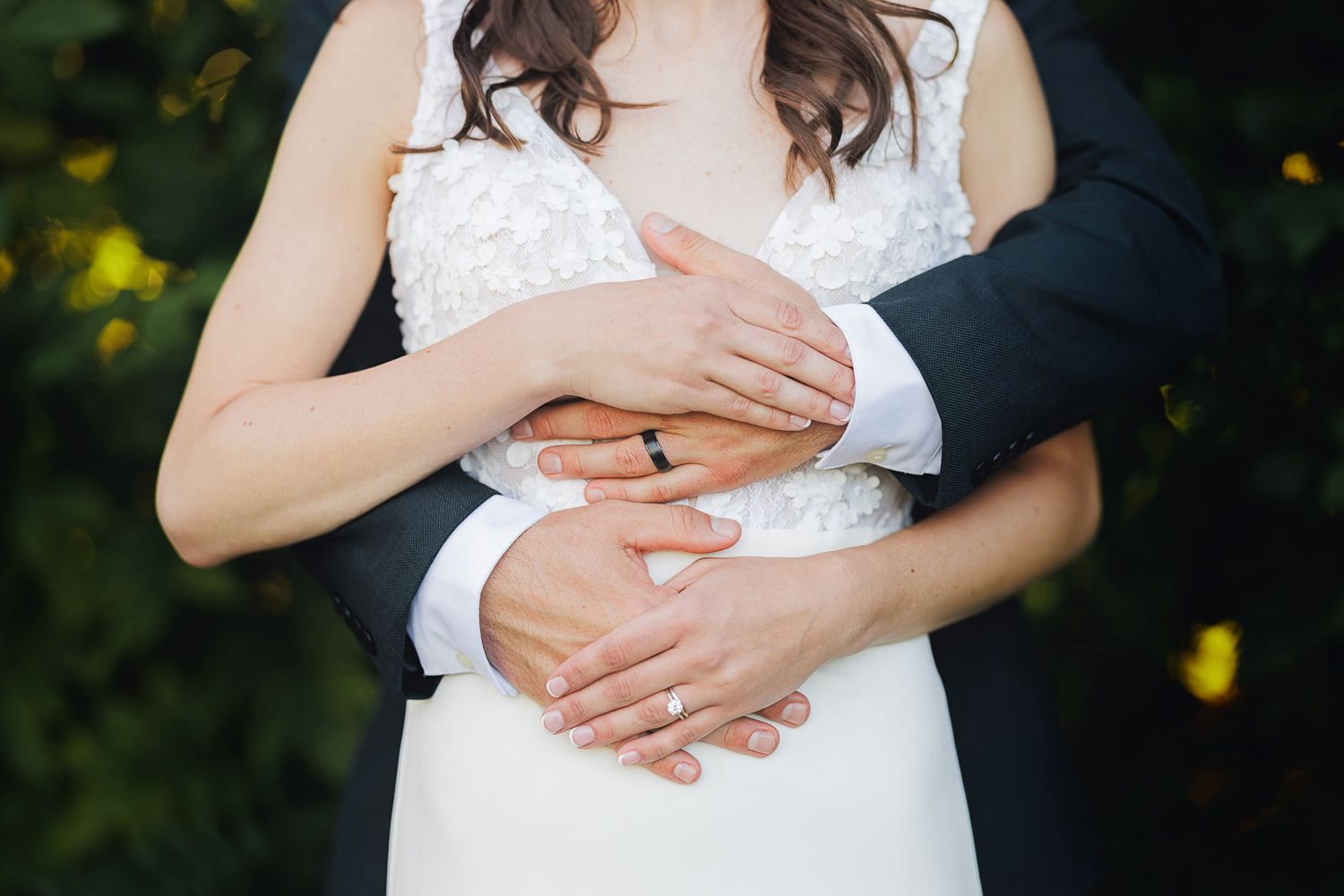 A romantic wedding couple embraces in a garden setting with yellow flowers in the background.