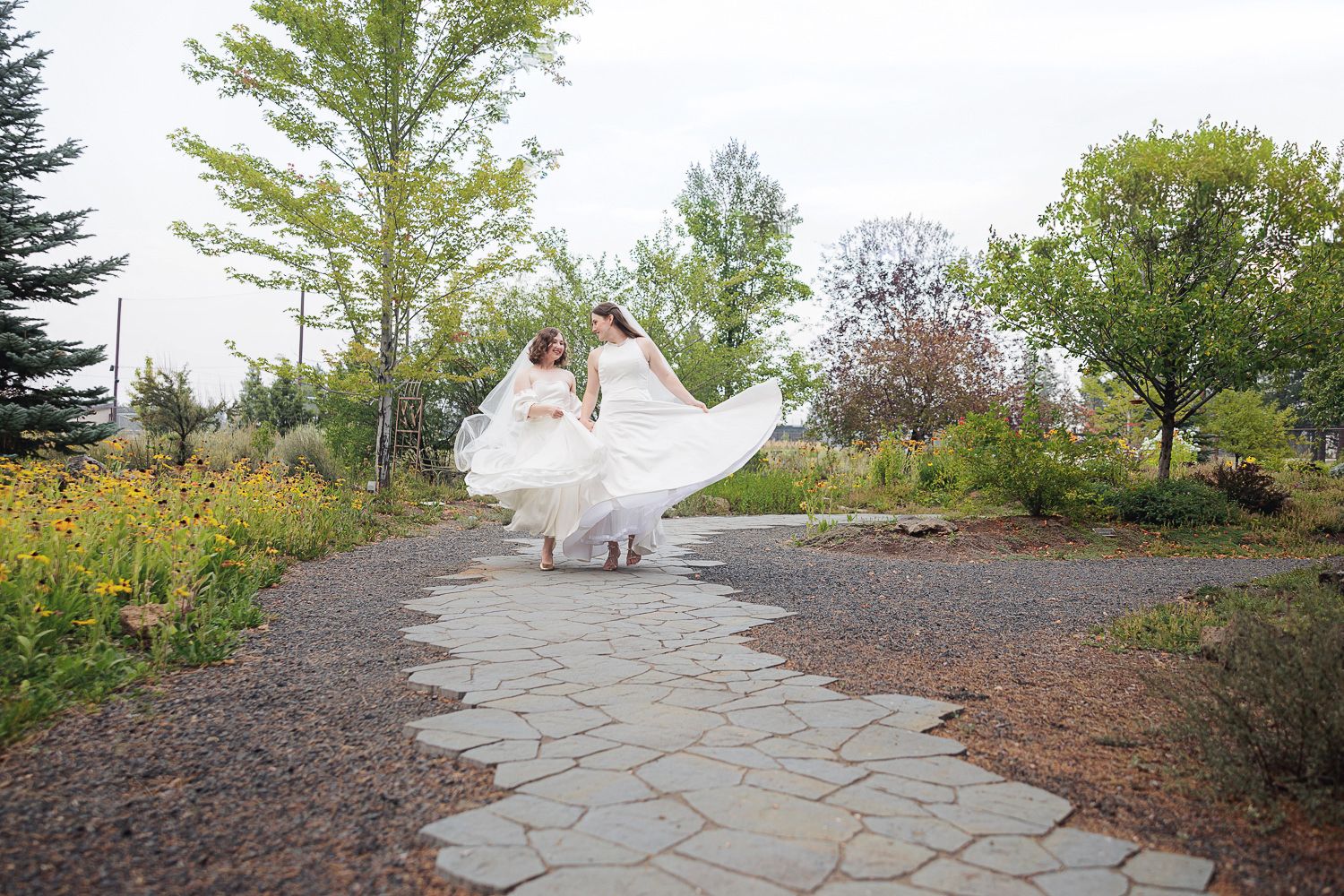 A stone pathway winding through a landscaped garden area with trees and natural vegetation.
