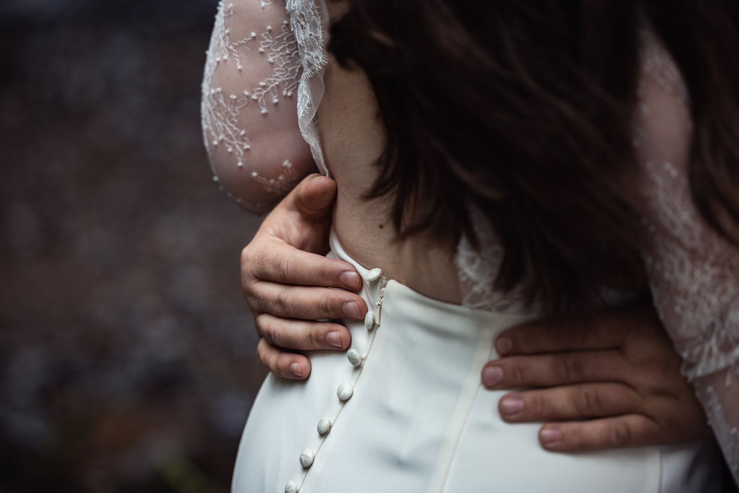 Close-up view of hands adjusting a vintage-style white corset dress with delicate lace details.