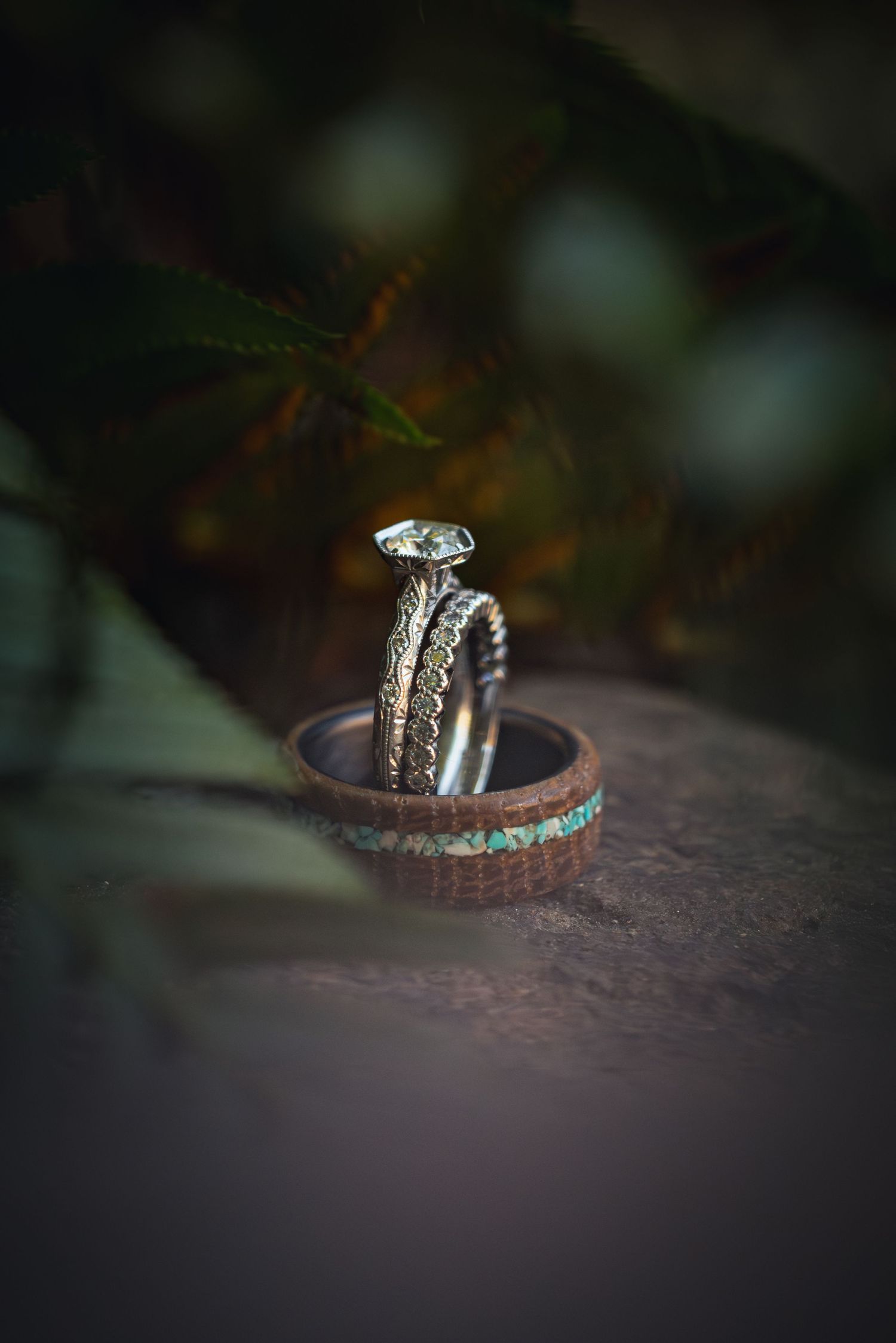 Diamond engagement ring and wedding band with intricate details photographed in dramatic lighting against dark background.