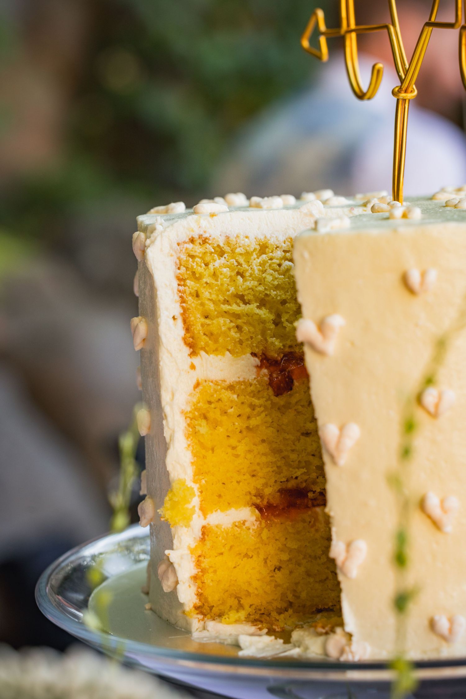 Close-up view of a sliced yellow layer cake with white frosting and delicate pearled decorations on the exterior.