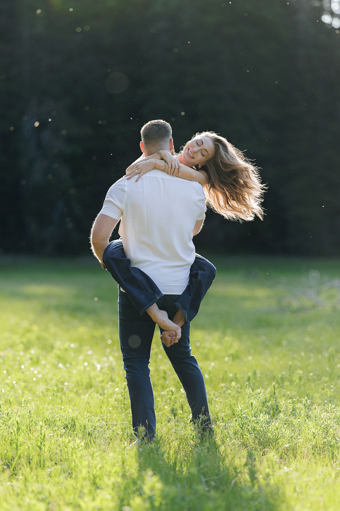 A couple embrace and dance together in a sunlit meadow on a warm summer evening.