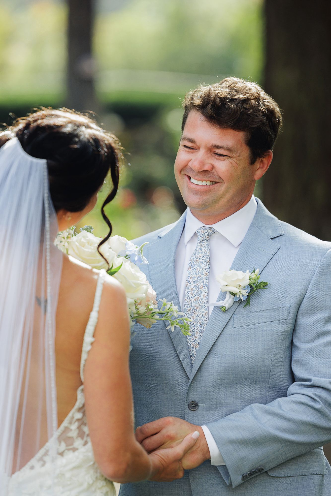 A couple shares intimate moments during their wedding photoshoot in light gray and white attire.