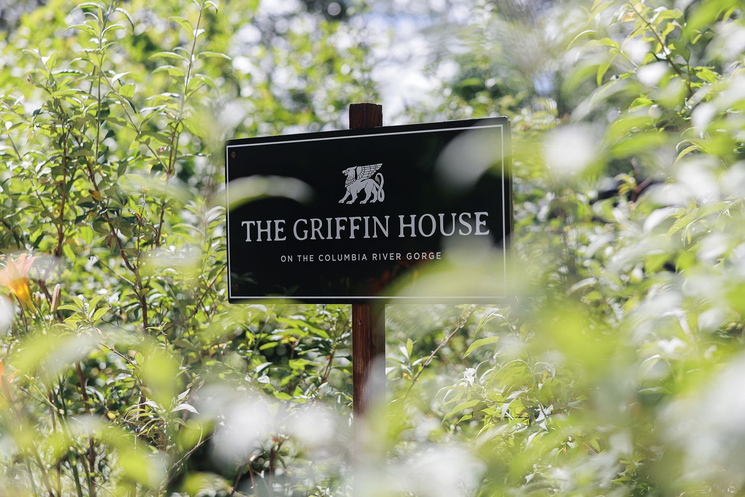 Sign for The Griffin House on the Columbia River Gorge surrounded by lush green foliage.