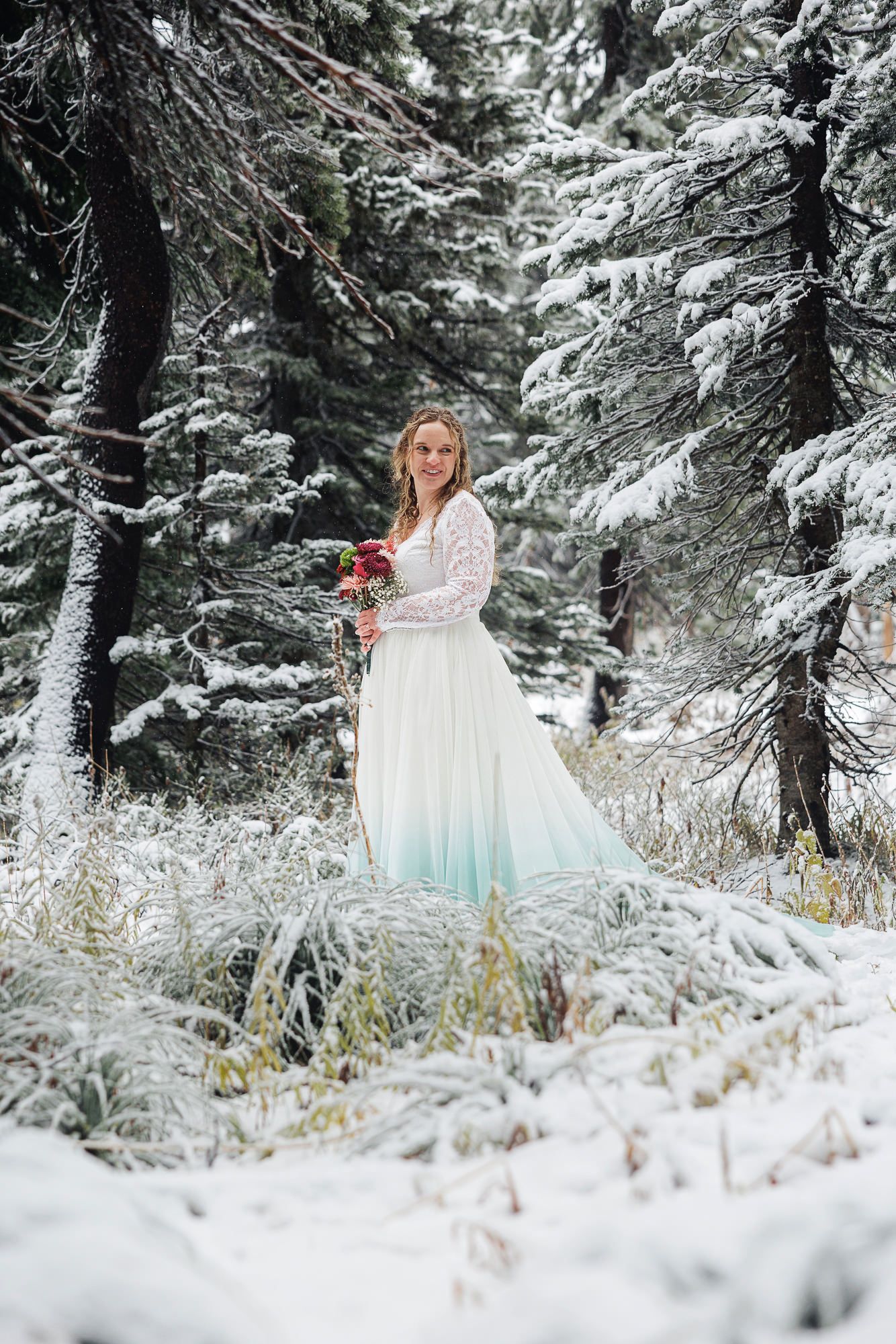A wedding dress with ombre blue details photographed in a magical snow-covered forest setting.
