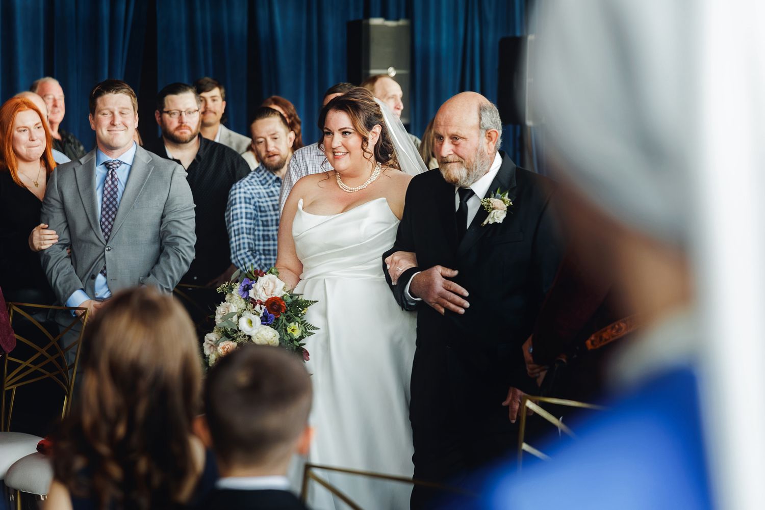 Wedding party members share joyful laughter during a candid moment at an indoor celebration.