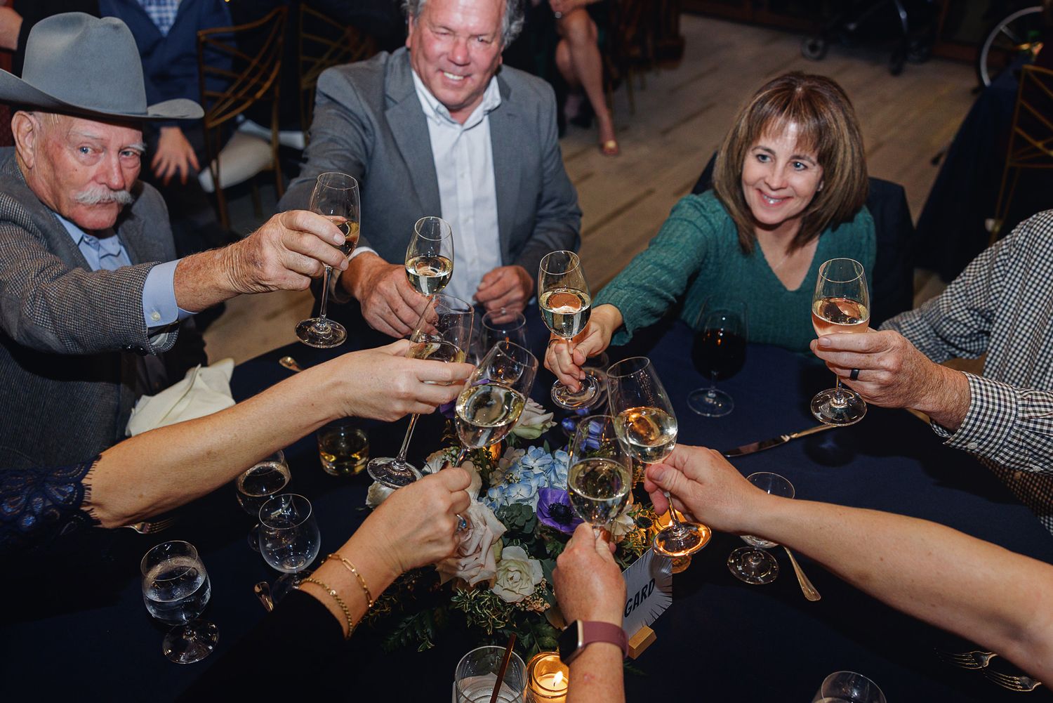 People raising wine glasses in a toast at a social gathering during a celebratory event.
