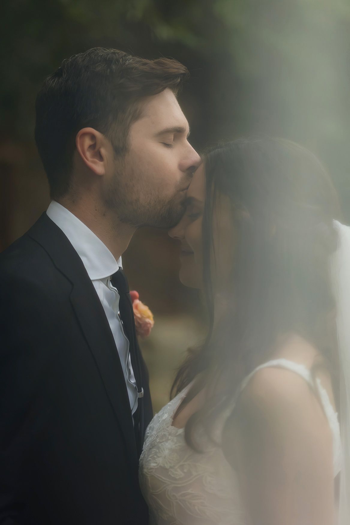 An intimate wedding photo showing a couple in formal attire behind frosted glass creating a dreamy effect.