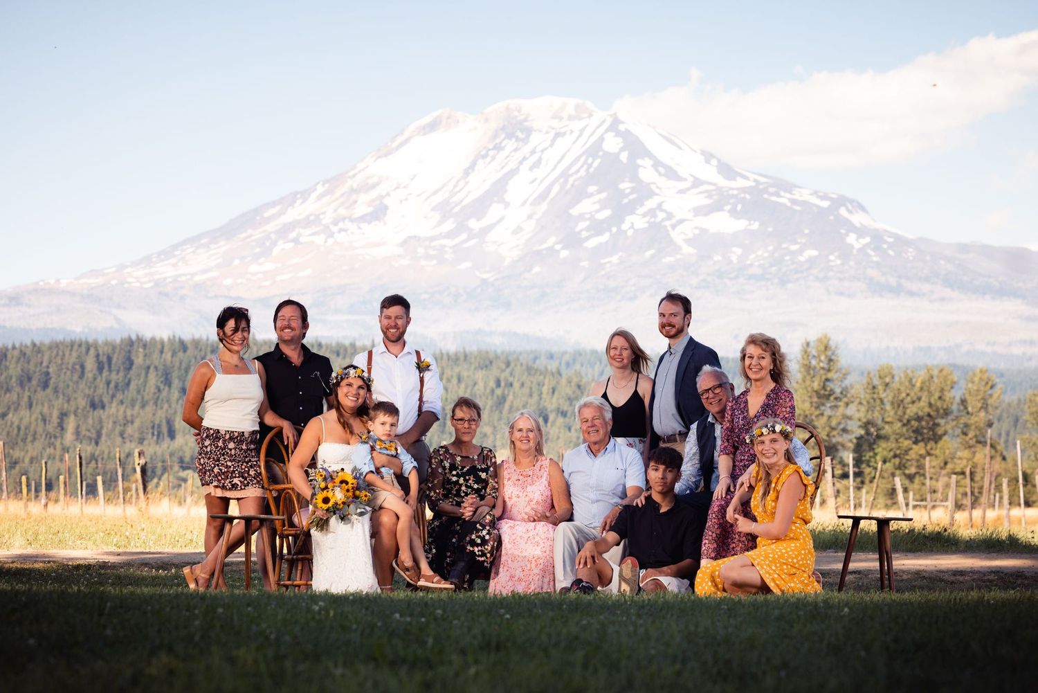 Group portrait with mountain backdrop taken during sunset at an outdoor wedding celebration.
