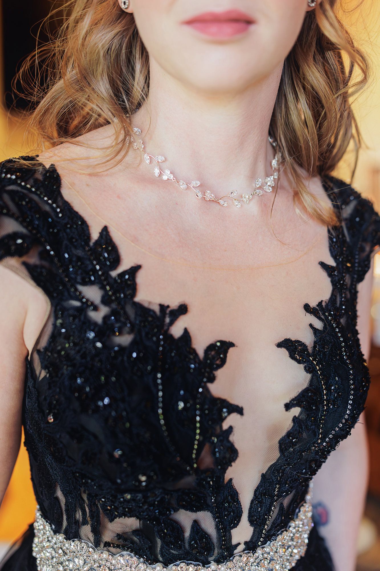 Woman wearing elegant black lace beaded gown with silver crystal necklace at formal event.