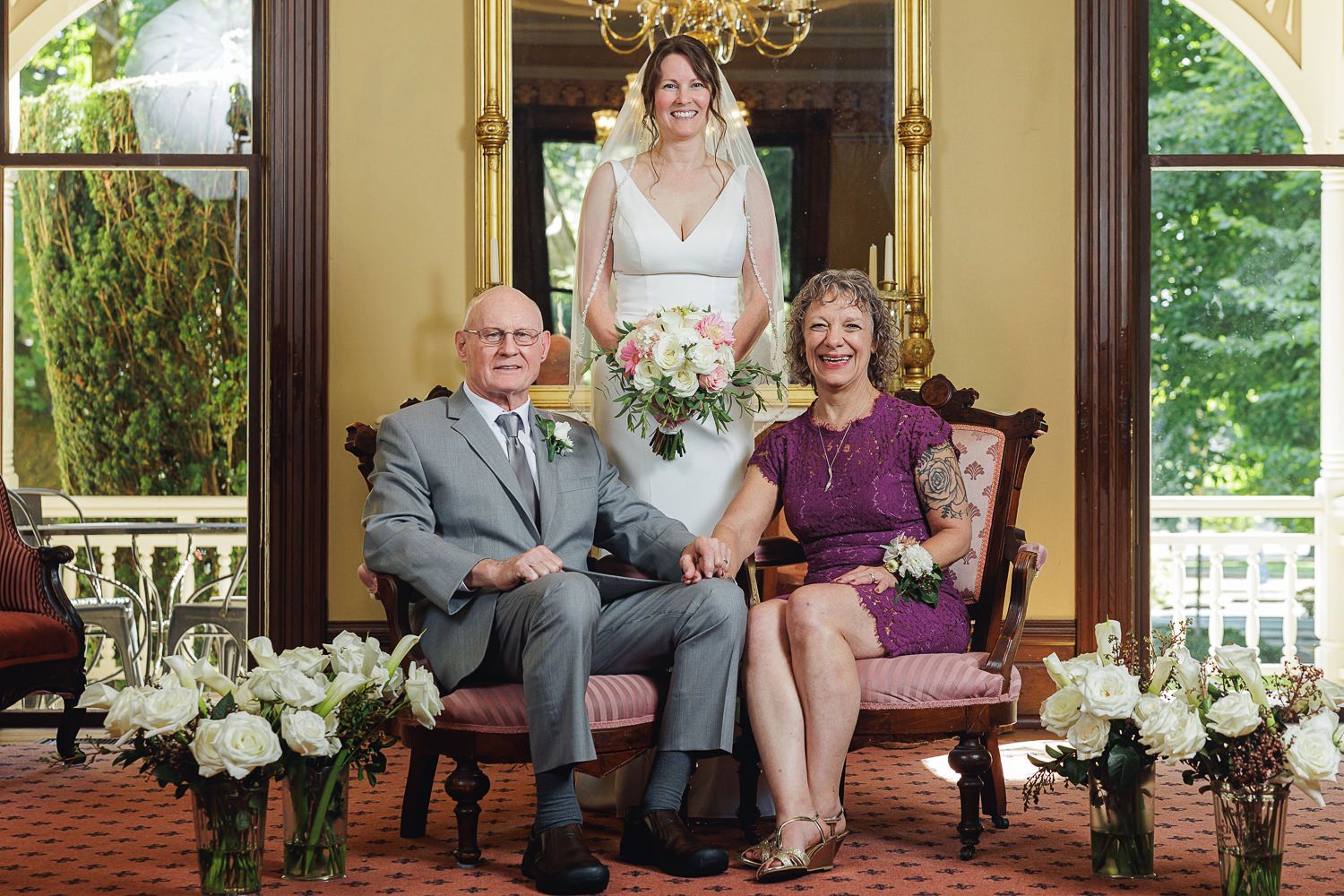A group sits together in an elegant ballroom with gold accents and chandelier lighting in formal attire.