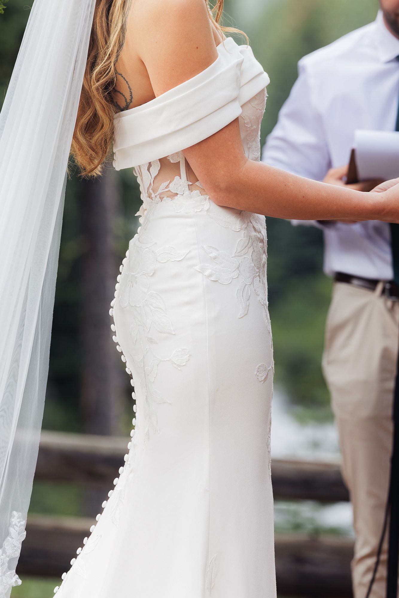 Close-up view of a bride in a white wedding dress with delicate lace details and flowing veil.