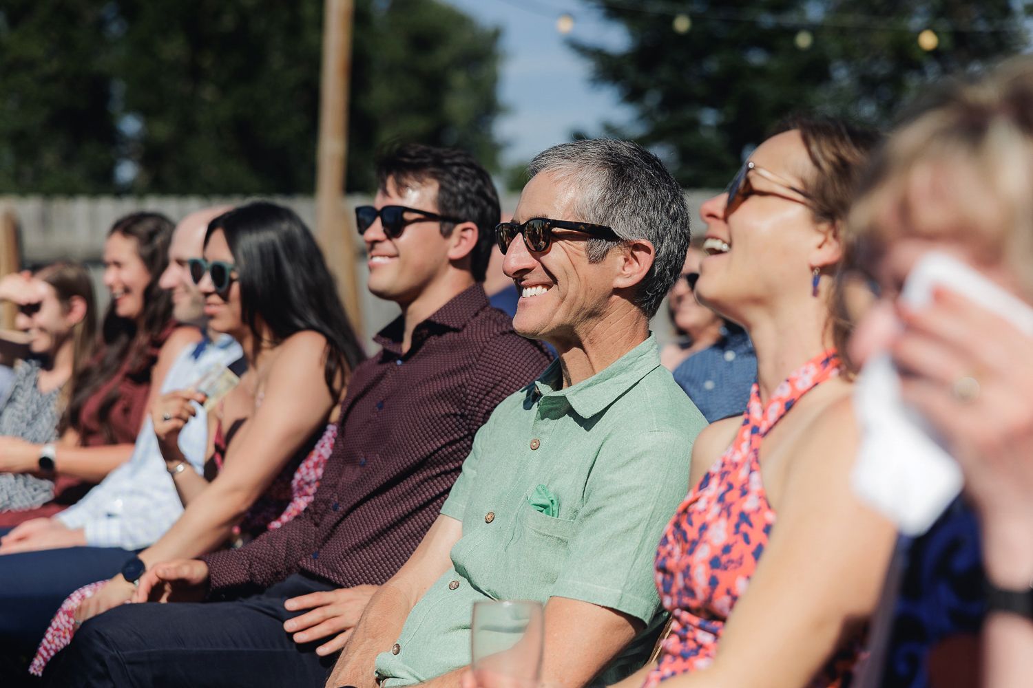 Wedding guests sitting in rows of chairs at an outdoor mountain venue while watching the ceremony.