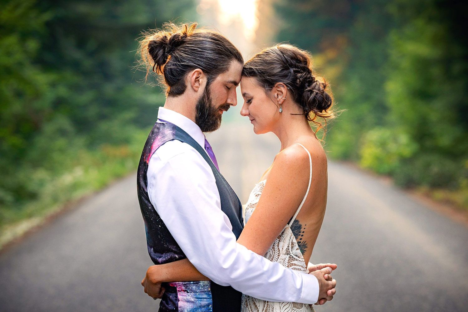 A romantic moment shared between newlyweds on a tree-lined country road.