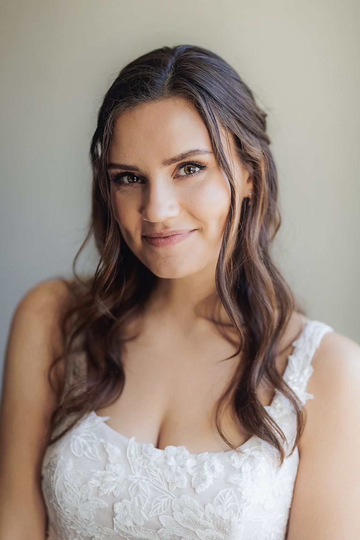 Portrait wearing white lace wedding dress with soft romantic hair styling.