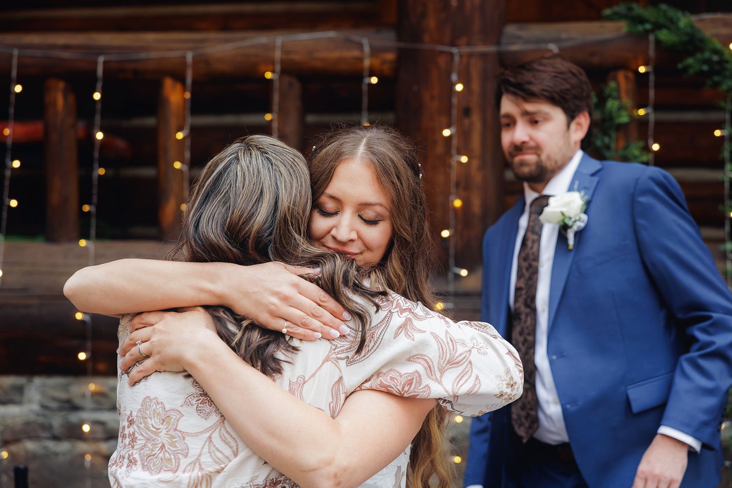 Couple embraces in an emotional dance during wedding reception with string lights in background.