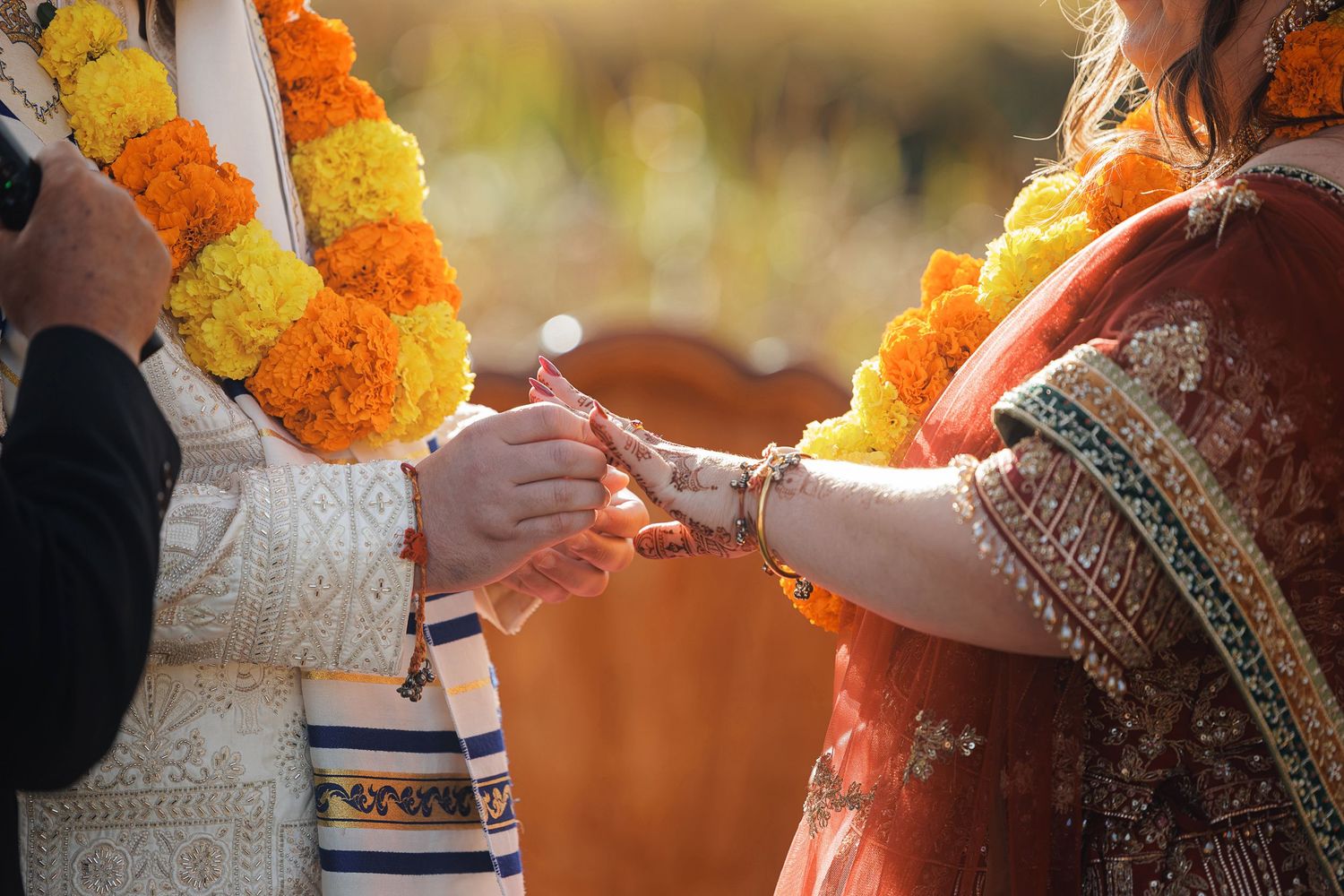 Indian wedding ceremony couple exchanging rings adorned with marigold flower garlands in traditional attire.