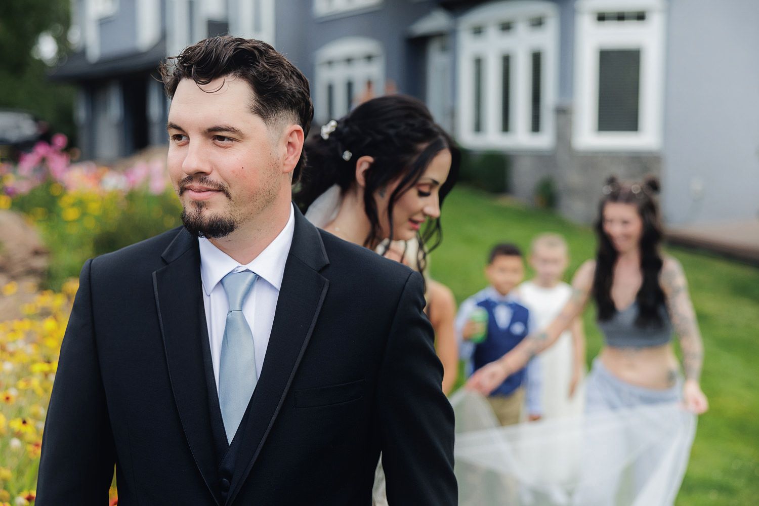 Wedding guests smile and chat while mingling on a grassy lawn during an outdoor celebration.