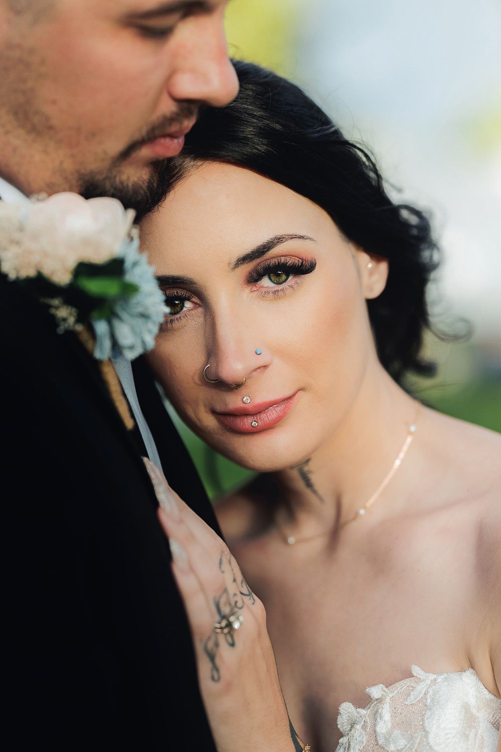 A romantic close-up portrait showcasing delicate makeup and nose piercing details against a soft natural background.