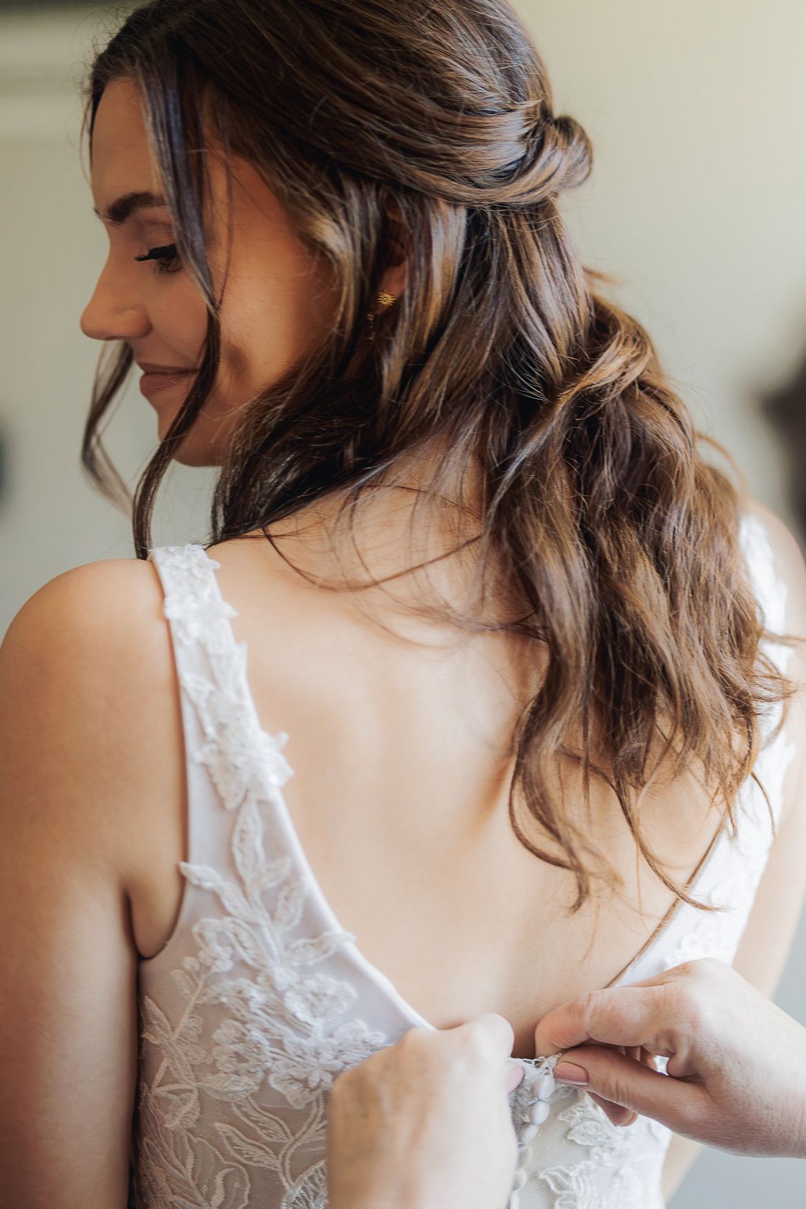 Close up of elegant bridal hairstyle with soft waves and lace dress detail.