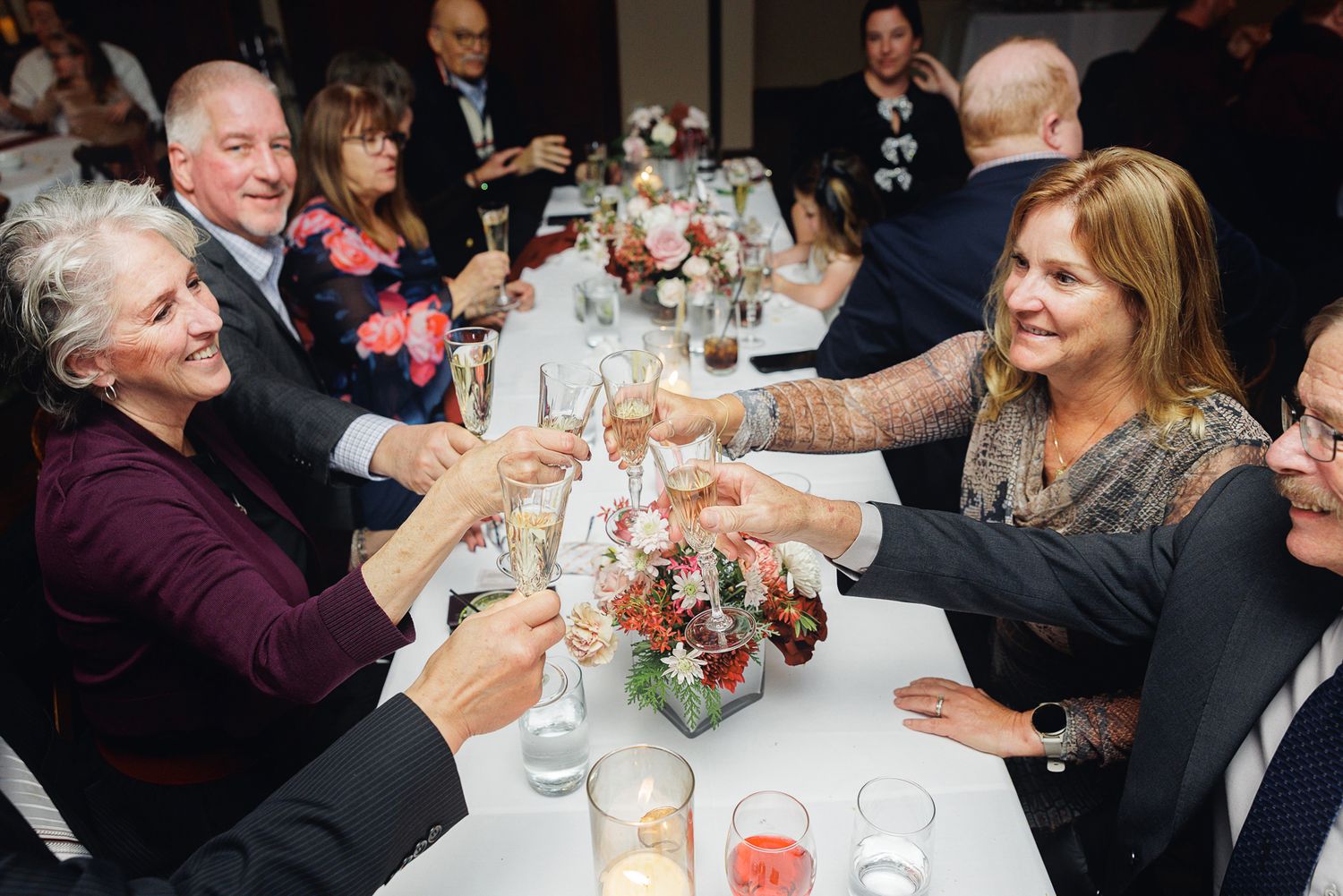 Wedding guests gathered around tables for dinner celebration in an elegant reception hall.