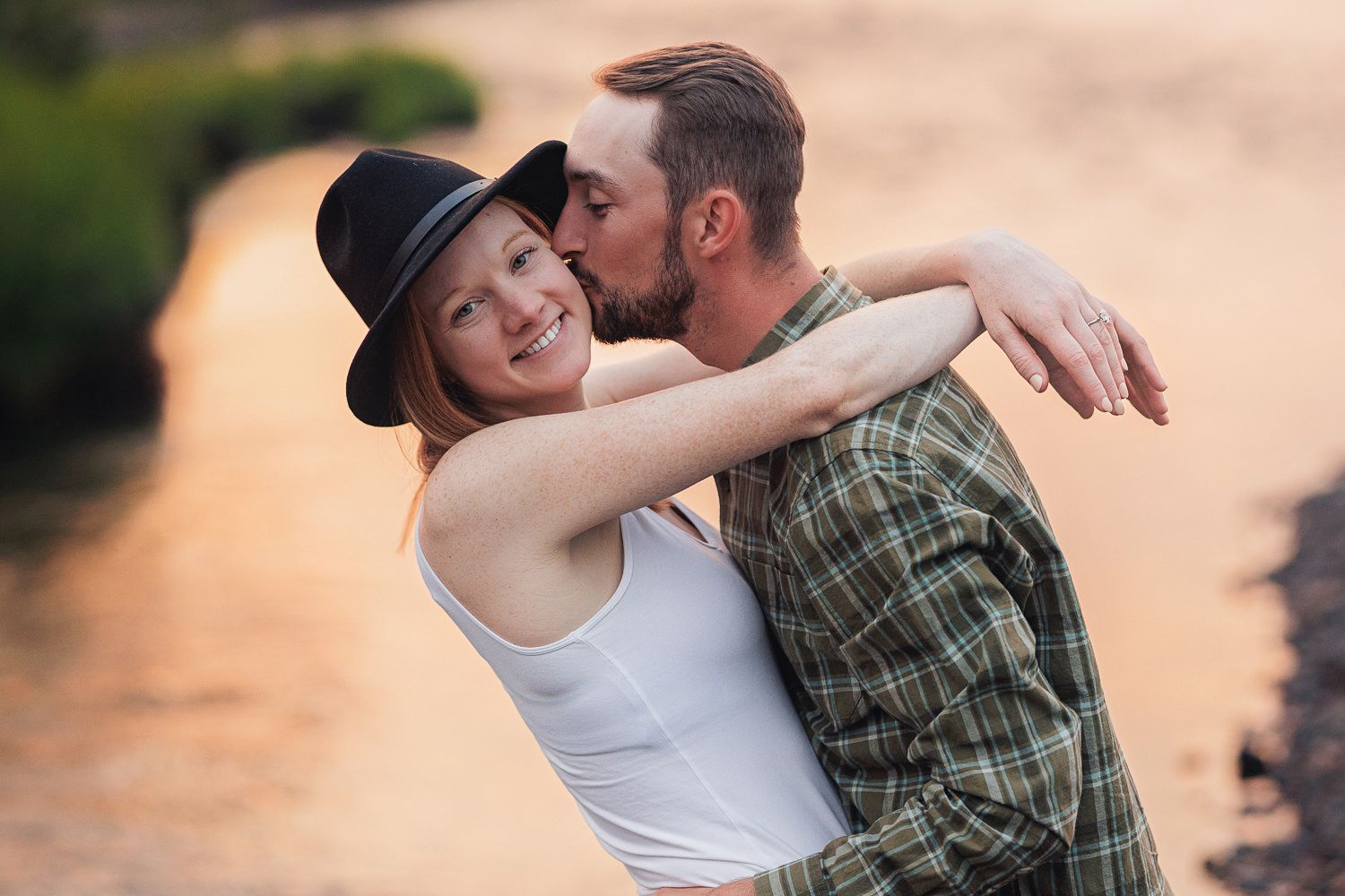 A couple sharing romantic moments together in a field during golden hour sunset lighting.
