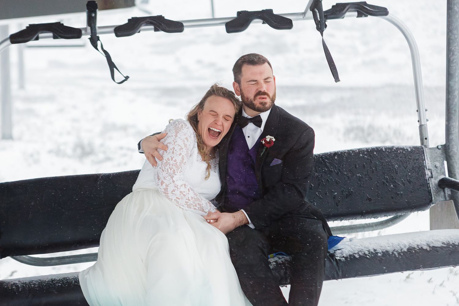 A couple shares a joyful moment together in the snow during their winter wedding celebration.