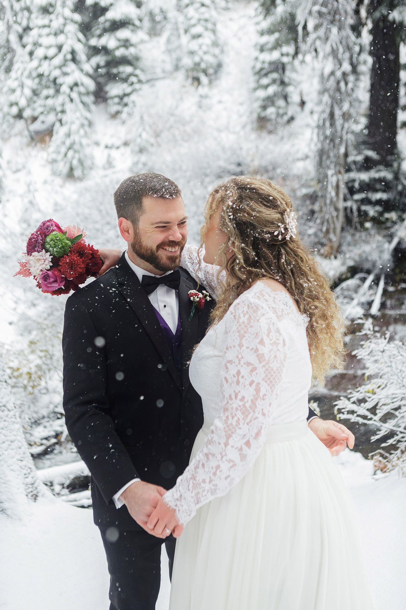 A couple shares intimate moments during their winter wedding photoshoot surrounded by snow-covered trees.