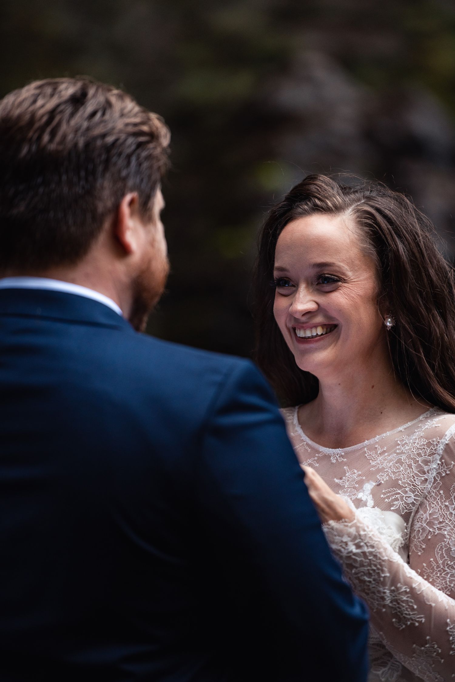 A couple sharing a joyful moment during their wedding ceremony, with the bride wearing a lace dress.