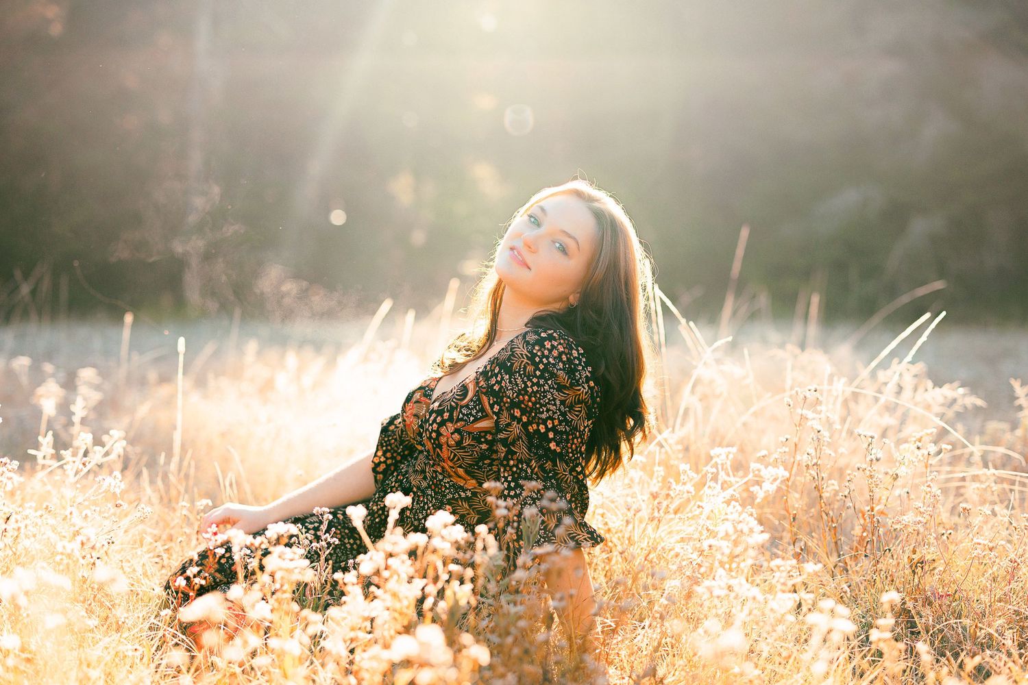 Dreamy portrait in tall grass with sunflare and dark clothing.