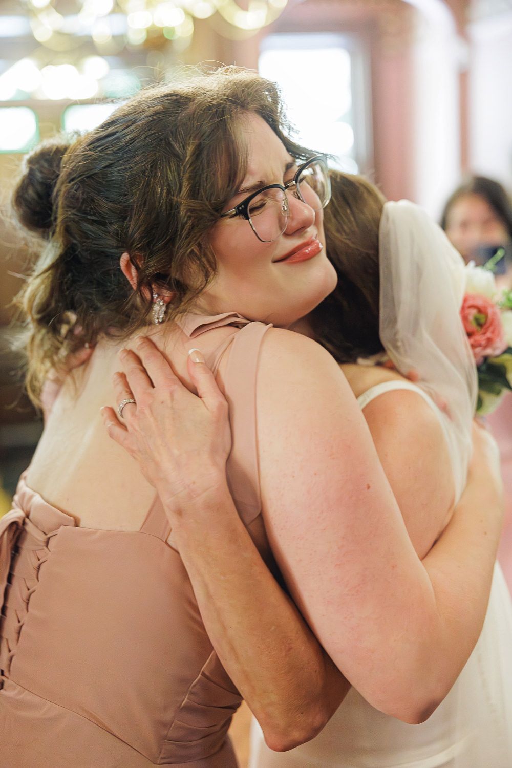 A series of emotional embraces showing two women in formal wear hugging warmly at what appears to be a wedding event.