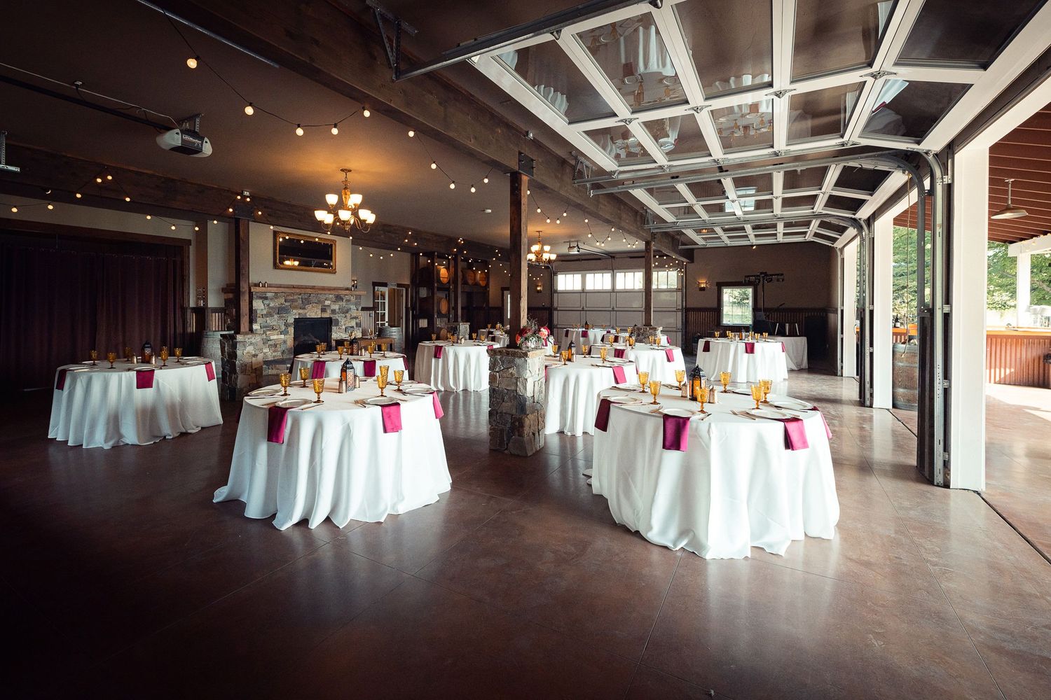 Empty event space with round tables covered in white tablecloths and industrial-style ceiling.